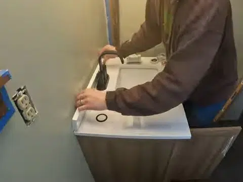Technician connecting a small bathroom sink drain and faucet for index in Stanton