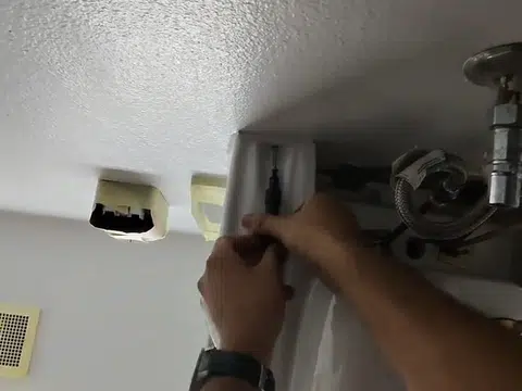 Commercial plumber working around overhead pipe runs for plumbing blog index in Stanton