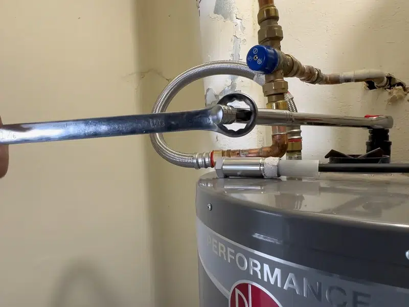 Plumber removing a depleted anode rod from water heater top for how long do water heaters last orange county in Stanton