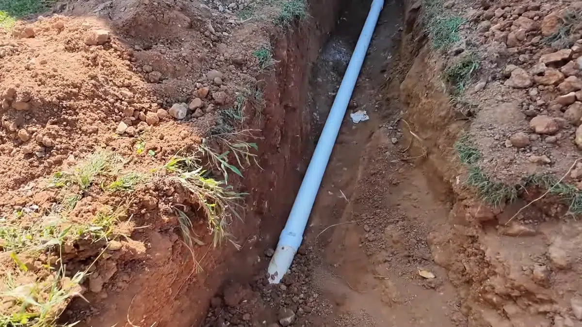 Blue replacement pipe laid in open dirt trench for sewer line replacement in Stanton