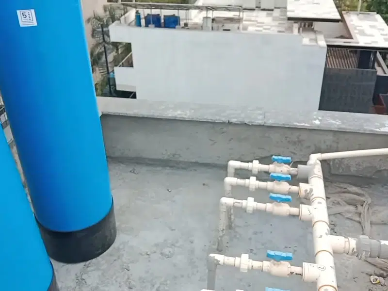 Blue outdoor water softener tank on rooftop plumbing lines for seal beach in Seal Beach