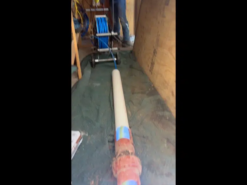 Technician handling pipe liner material at sewer repair access for magnolia street area in Magnolia Street Area, Stanton