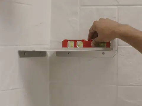 Level placed on shower wall shelf during installation for index in Stanton